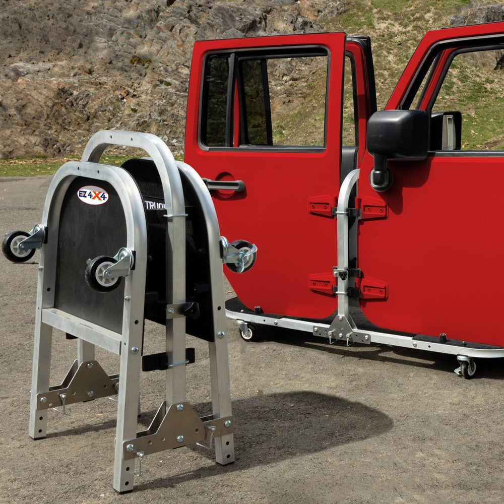 Red Jeep doors stored on EZ4X4 silver door cart; second cart folded for compact, space-saving storage solution.