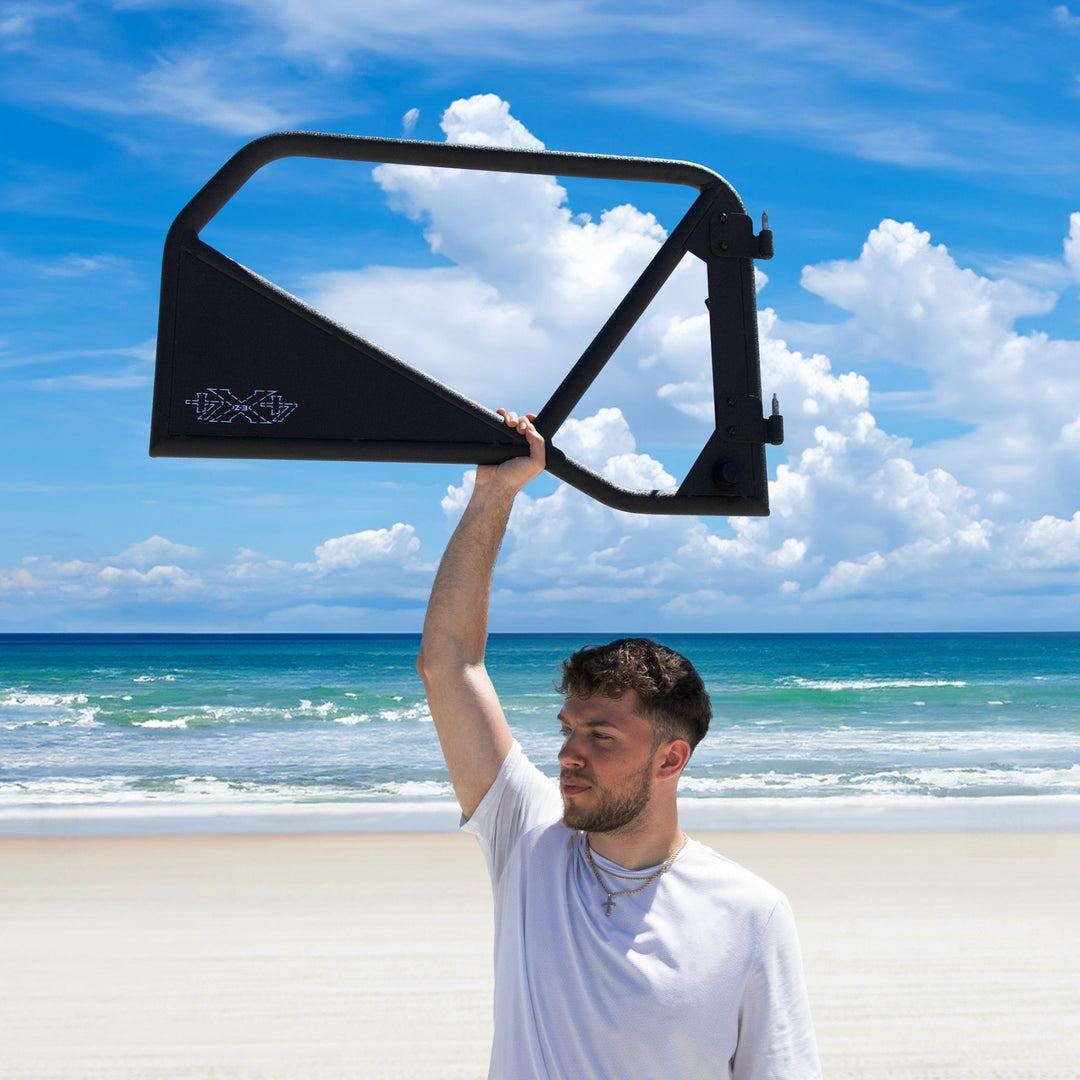 Man lifting black Phantom aluminum door overhead, showcasing lightweight, removable design and rugged durability.