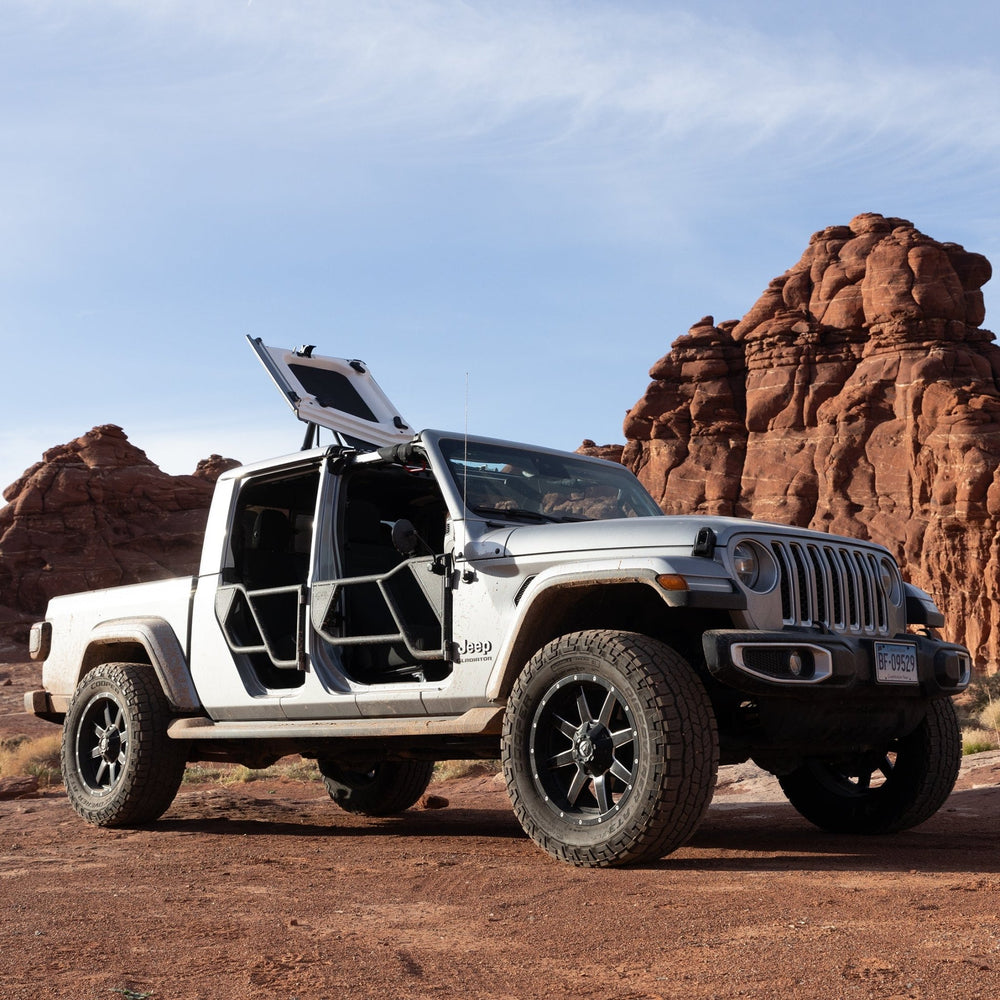 White Jeep Gladiator with EZ4X4 Razor half-tube doors and FlipTop open, parked in desert with red rock formations.