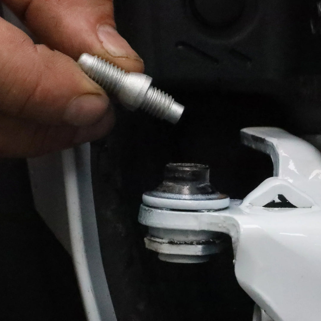 Close-up of hand inserting door alignment pin into Ford Bronco hinge, highlighting precise fit and installation process.