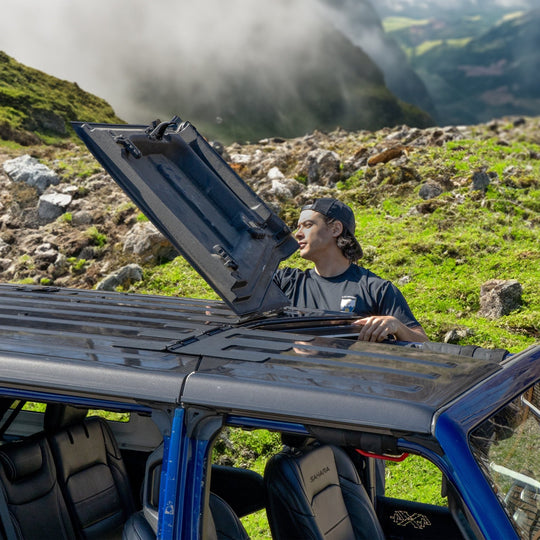 Man flipping back Freedom Panels of a Jeep outdoors, showing easy roof opening for ventilation and open-air driving.