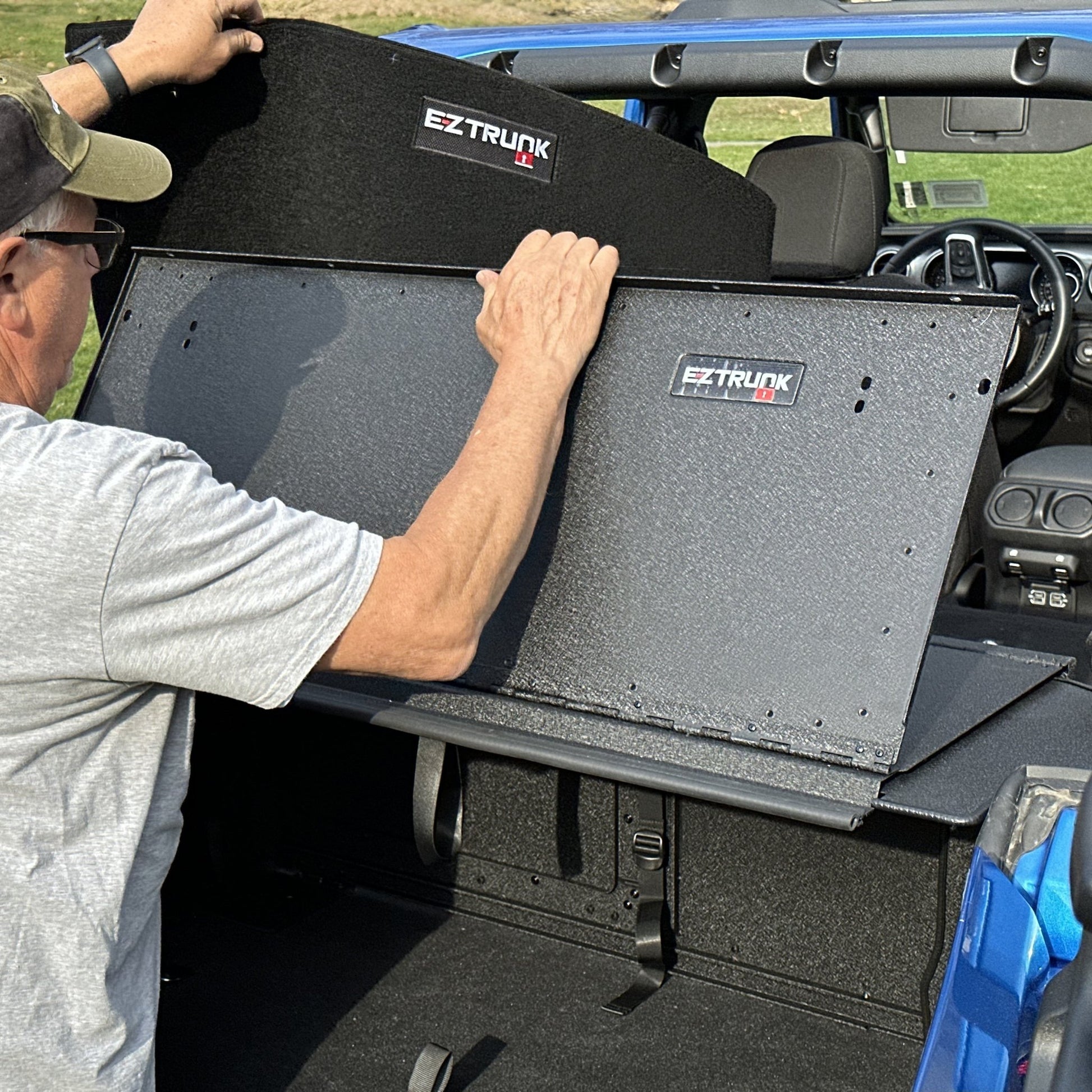 Man installing custom-fit carpet kit in EZ trunk, demonstrating easy install and durable interior protection.