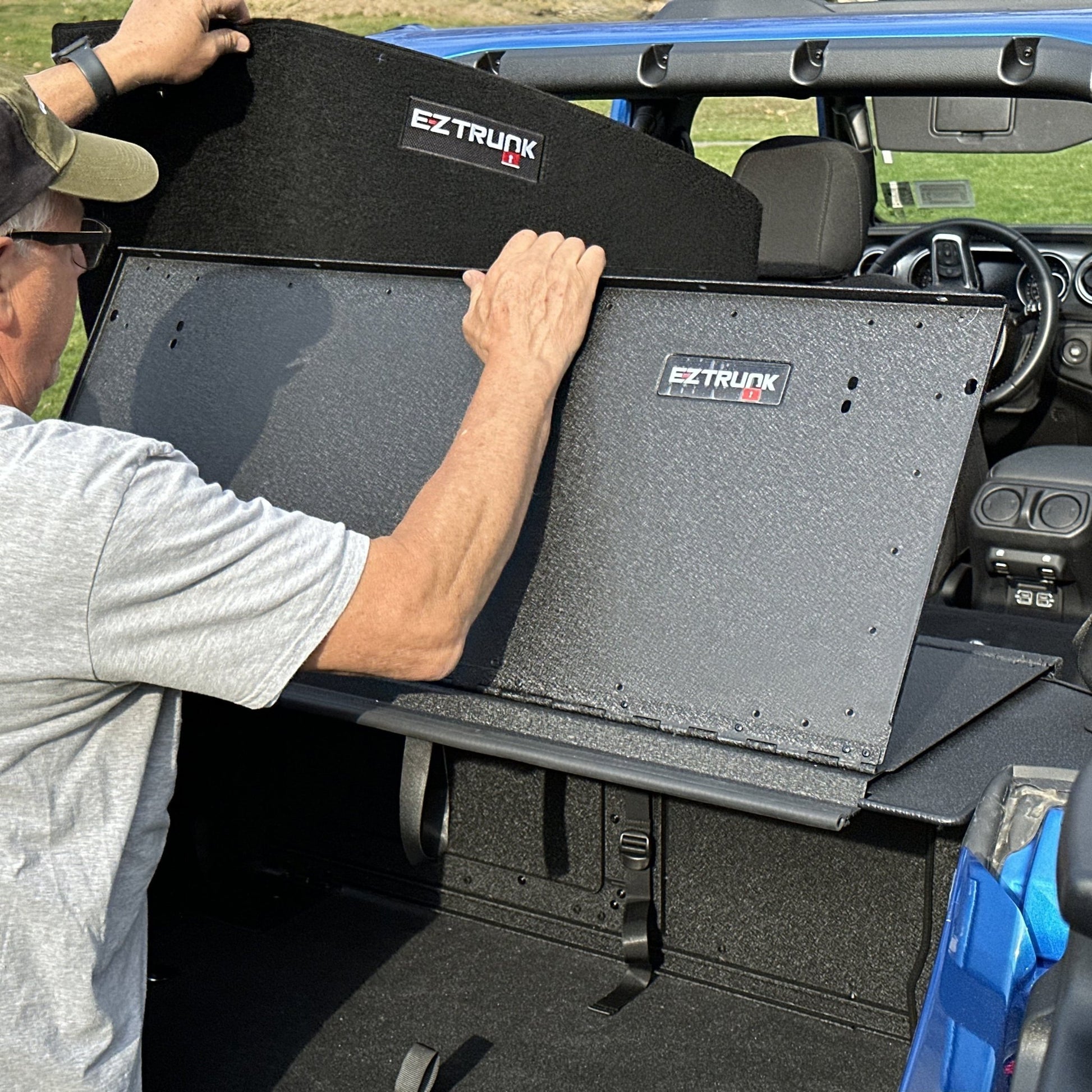 Man installing custom-fit carpet kit in EZ trunk, demonstrating easy install and durable interior protection.
