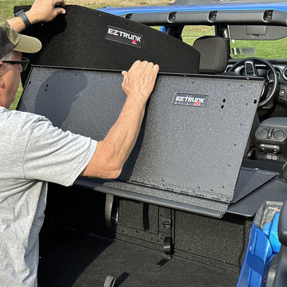 Man installing custom-fit carpet kit in EZ trunk, demonstrating easy install and durable interior protection.