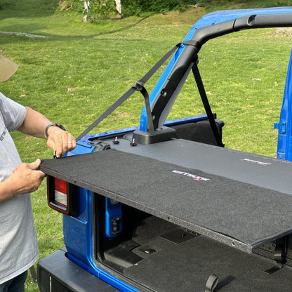 Man demonstrating easy install of custom-fit carpet kit in EZ trunk, showcasing durable interior protection and style.