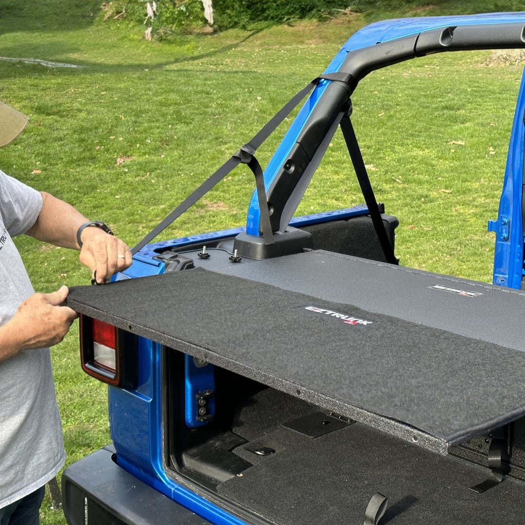 Man demonstrating easy install of custom-fit carpet kit in EZ trunk, showcasing durable interior protection and style.
