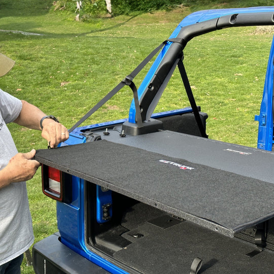 Man demonstrating easy install of custom-fit carpet kit in EZ trunk, showcasing durable interior protection and style.