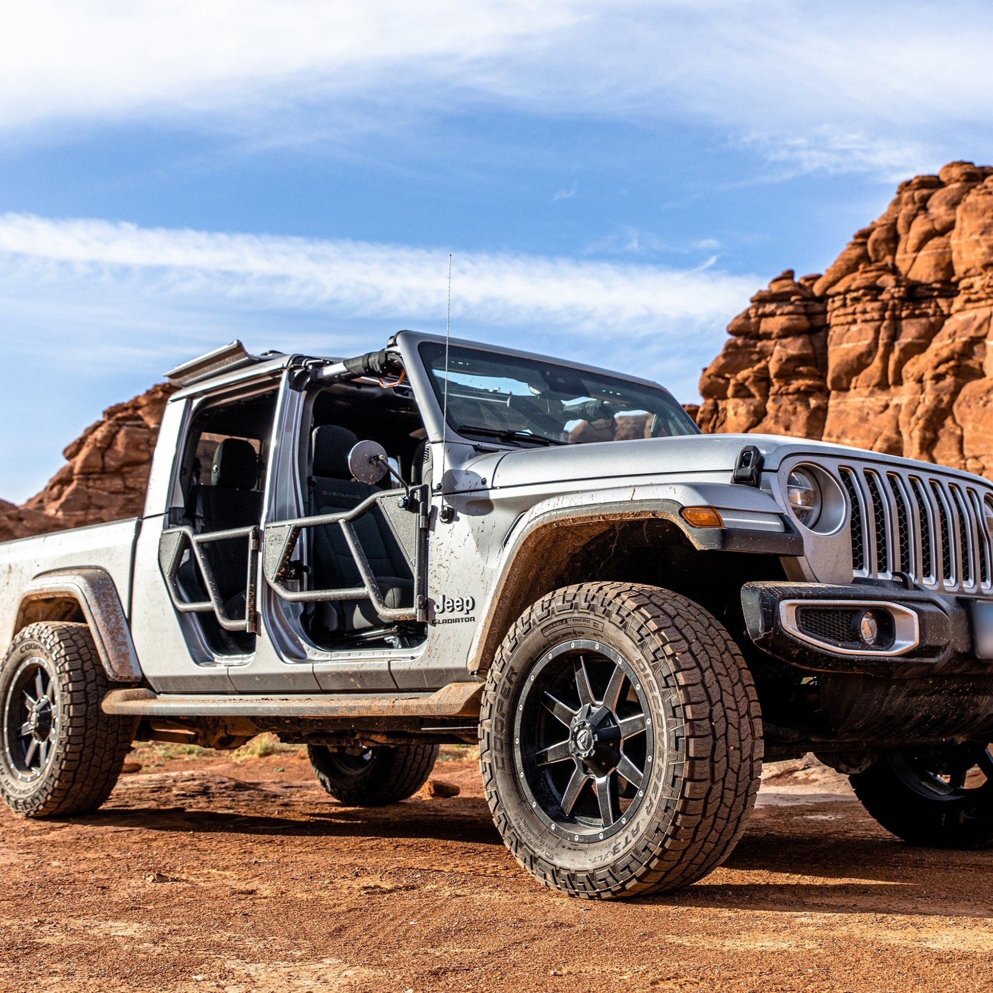 Silver Jeep Gladiator (JT) on a dirt trail, equipped with black EZ4X4 Razor Tube Doors and an EZ FlipTop.