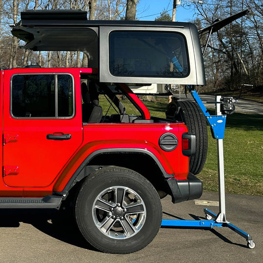 EZ4x4 blue steel hardtop lift holding Jeep hardtop above red vehicle, for safe, easy roof removal and storage.