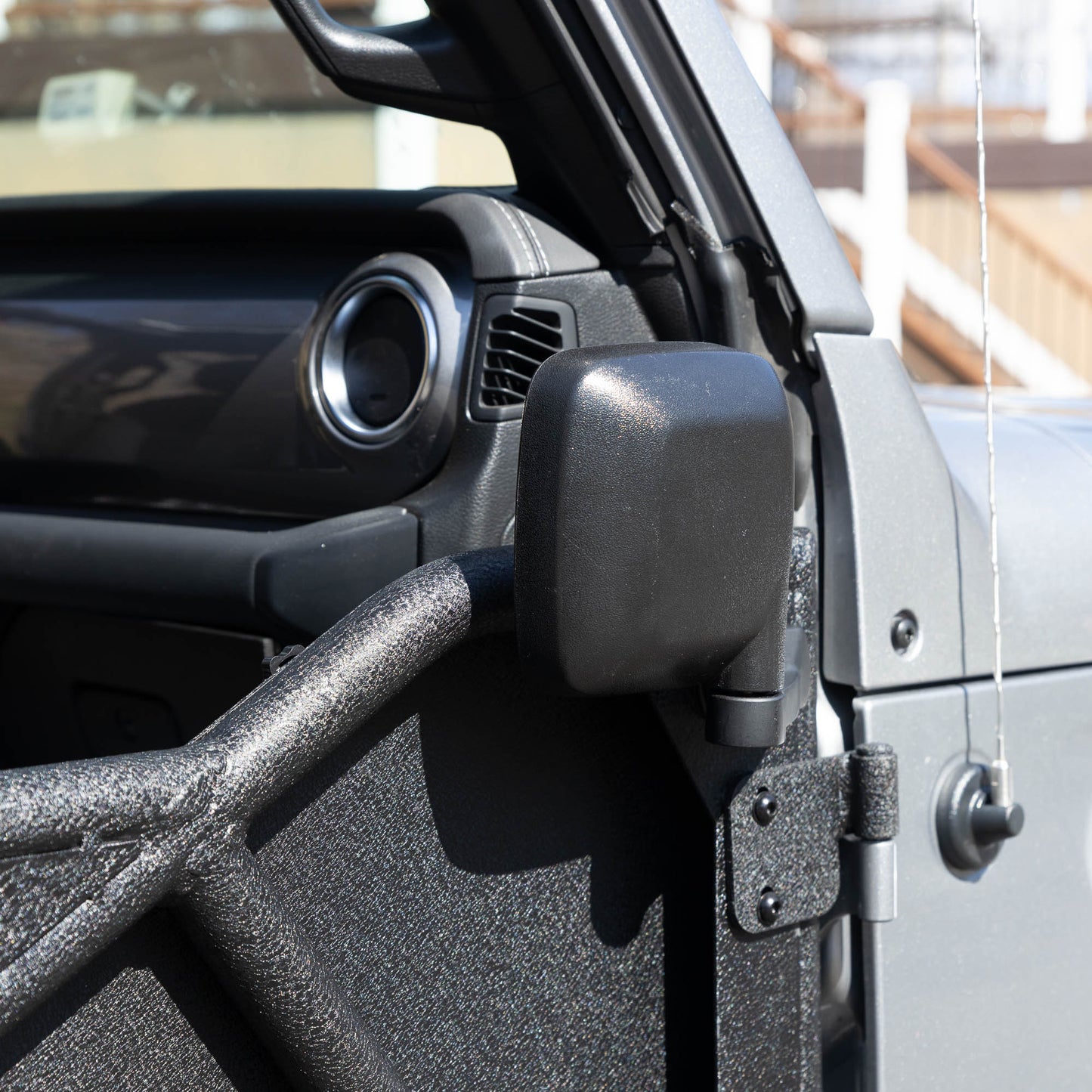 Rectangular aluminum side mirror folded up on white Jeep, showcasing durable aftermarket design and off-road readiness.