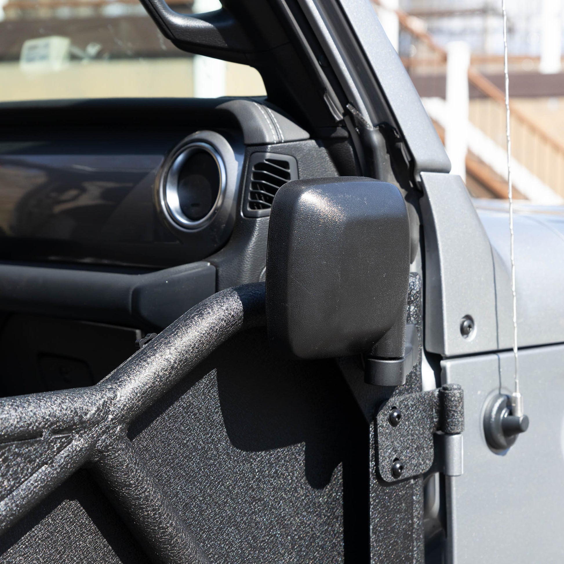 Rectangular aluminum side mirror folded up on white Jeep, showcasing durable aftermarket design and off-road readiness.