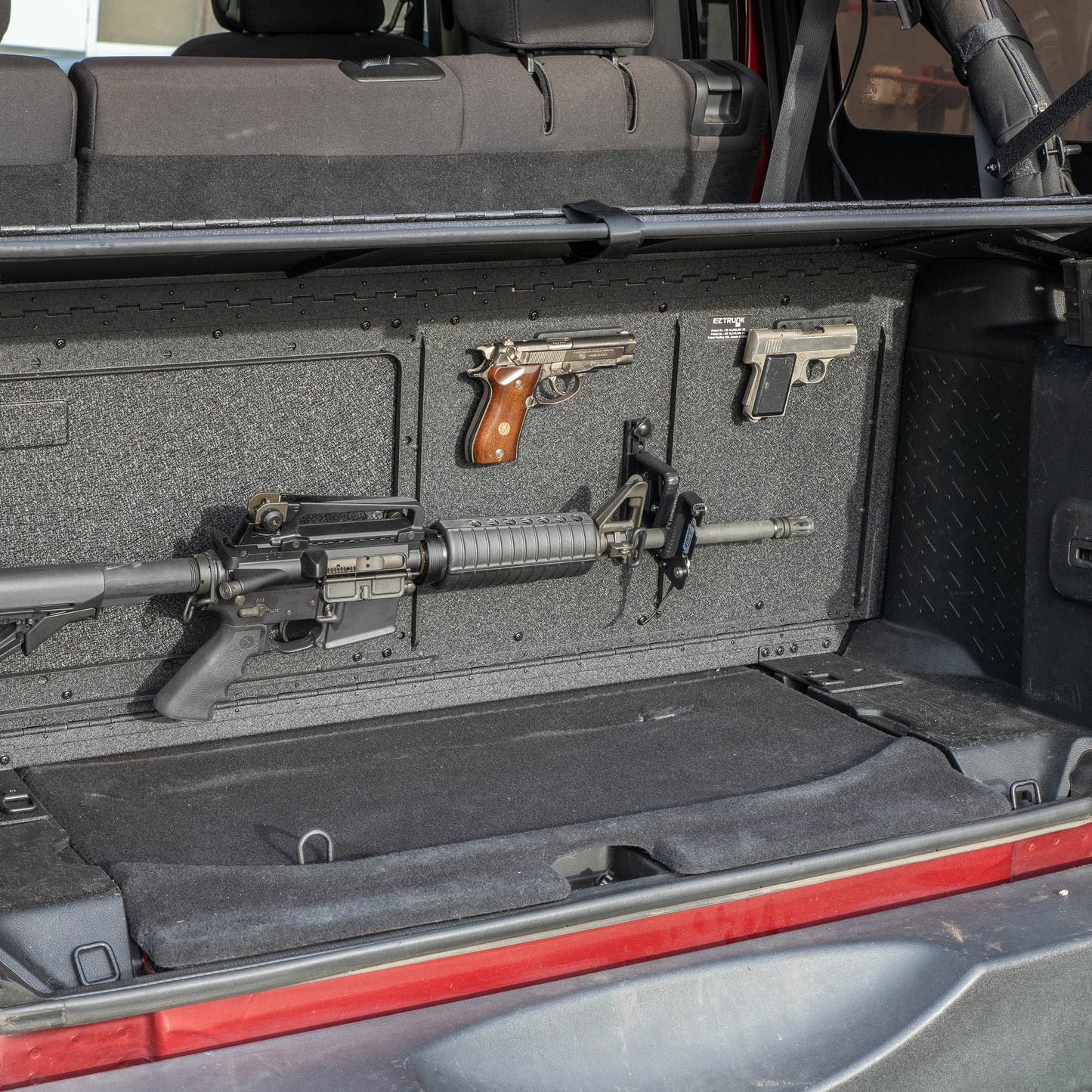 EZTRUNK storing multiple firearms secured with EZ4X4 gun magnets and mounted gun holders inside the cargo area of a vehicle.