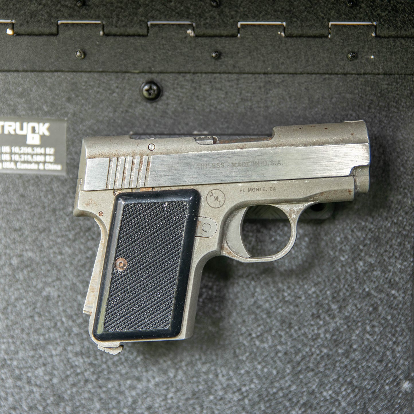 Close-up of the EZ4X4 gun magnets securing a silver handgun to the interior wall of the EZTRUNK storage system.
