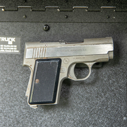 Close-up of the EZ4X4 gun magnets securing a silver handgun to the interior wall of the EZTRUNK storage system.