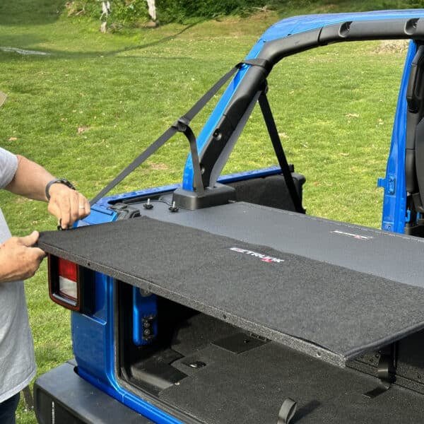 Man demonstrating how to attach EZTrunk Extension Table using straps, showing simple, secure setup for added functionality.
