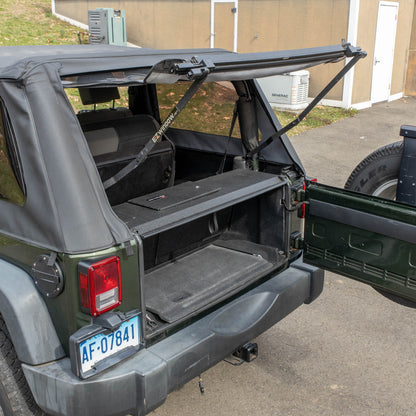 Side view black EZTrunk installed in cargo area of green Jeep Wrangler with trunk door open, showing secure storage setup.