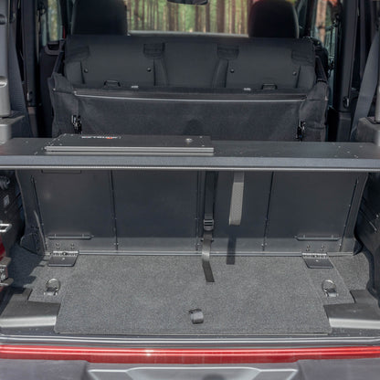 Straight-on view of black EZTrunk in cargo area of red Jeep Wrangler with trunk door open, showing secure storage setup.