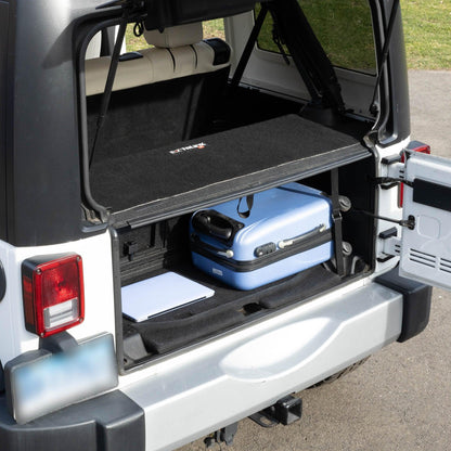 Side view of black EZTrunk installed with items inside cargo area of Jeep Wrangler with trunk door open, showing storage use.
