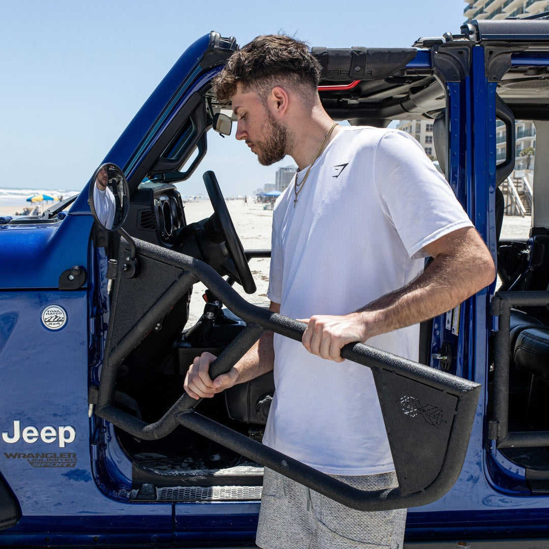 Man installing EZ4X4 Razor half-tube aluminum doors on blue Jeep, showcasing lightweight design and easy installation.