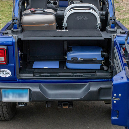 Black EZTrunk in blue Jeep Wrangler cargo area, shown in use with gear inside and folded flat for concealment.