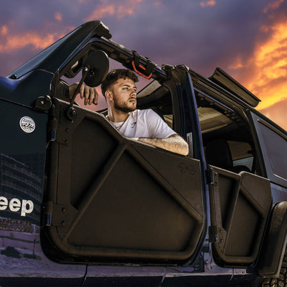 Man sitting in Jeep with black aluminum Phantom doors and all-weather panels installed, showcasing off-road-ready setup.