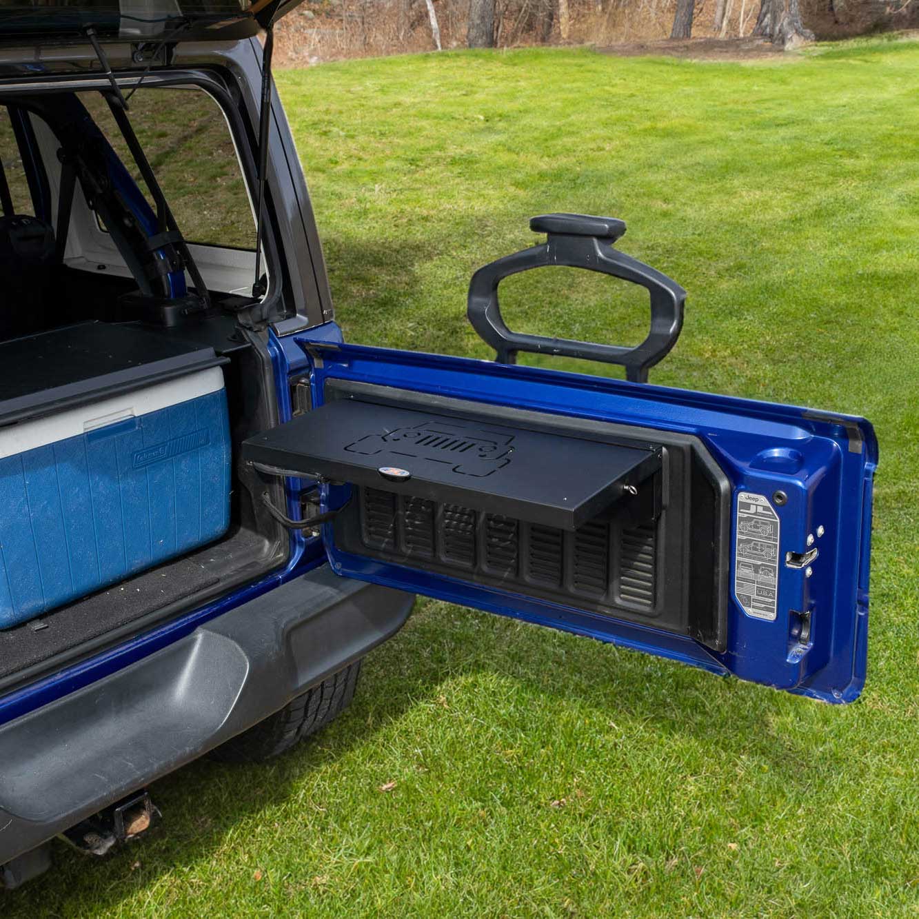 EZ4X4 Single Level Tailgate Table fully deployed on a blue Jeep Wrangler tailgate, with a cooler in the cargo area and a picnic setup for outdoor use.
