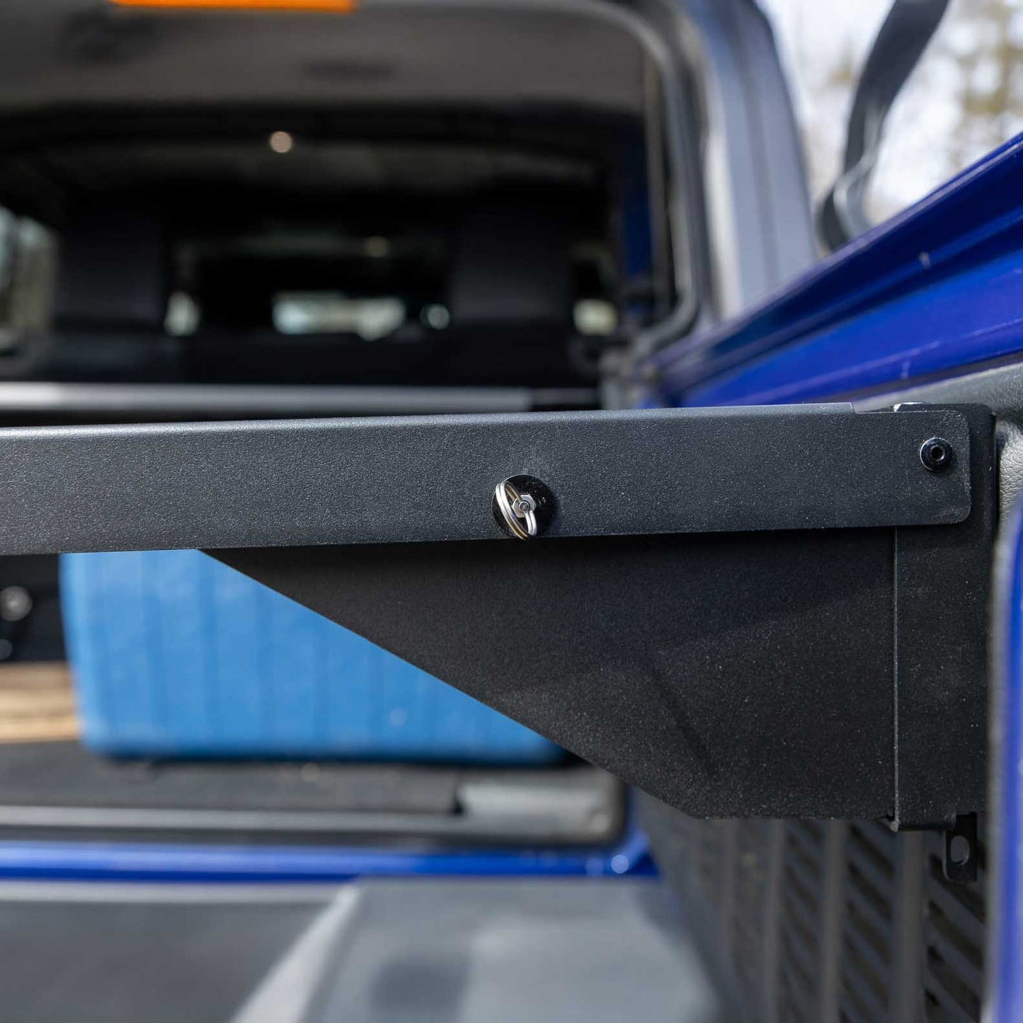 Close-up of the EZ4X4 Single Level Tailgate Table corner on a Jeep, showing the sturdy mounting bracket and latch mechanism for secure, space-saving storage.