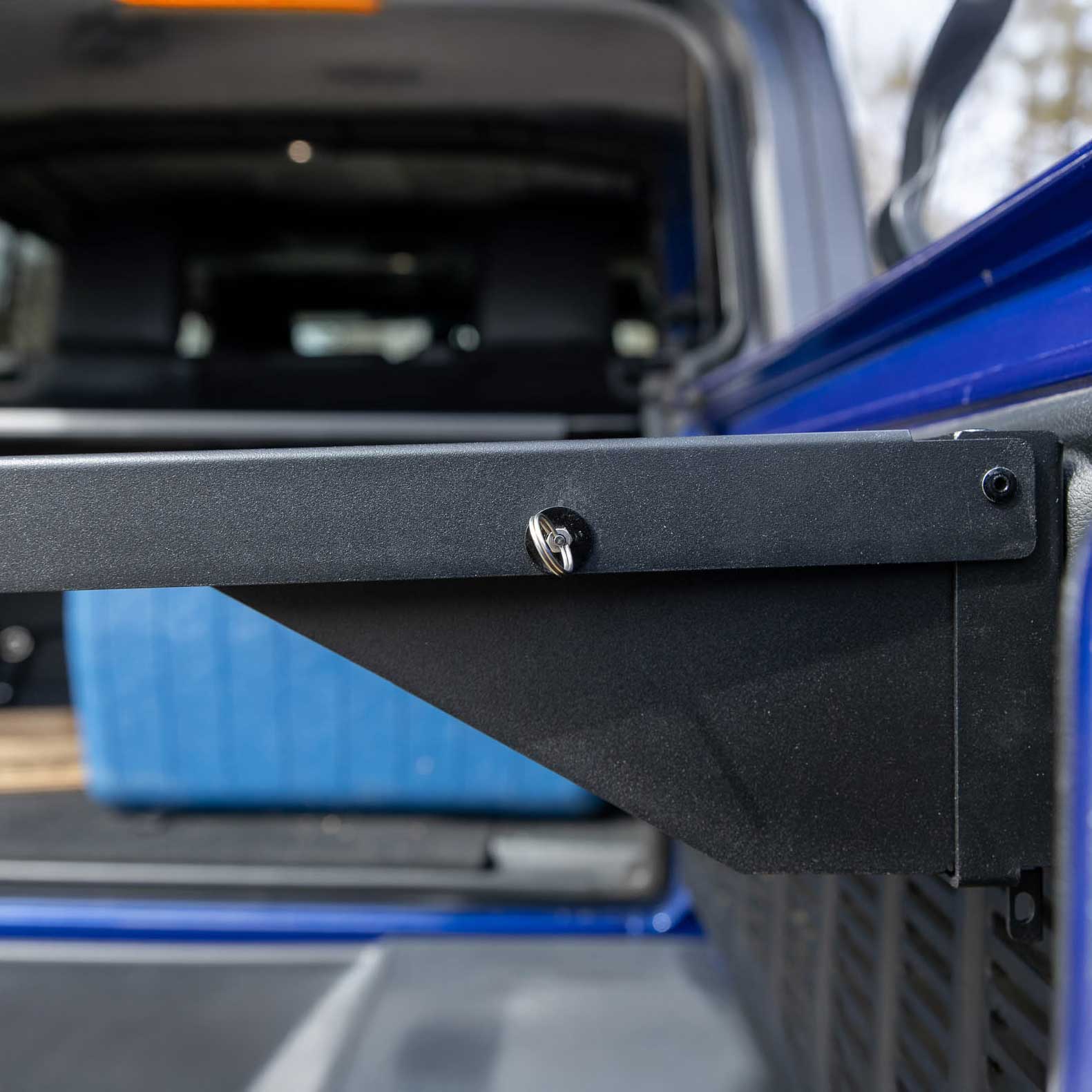 Close-up of the EZ4X4 Single Level Tailgate Table corner on a Jeep, showing the sturdy mounting bracket and latch mechanism for secure, space-saving storage.