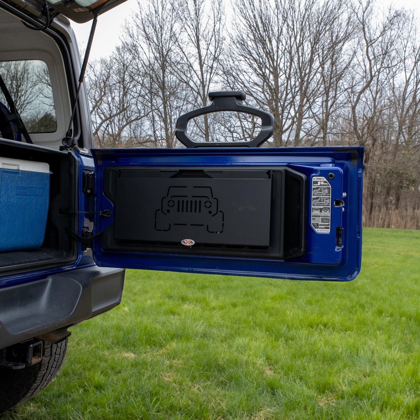 Tailgate table installed on Jeep shown folded up, highlighting space-saving design ideal for off-roading and camping.