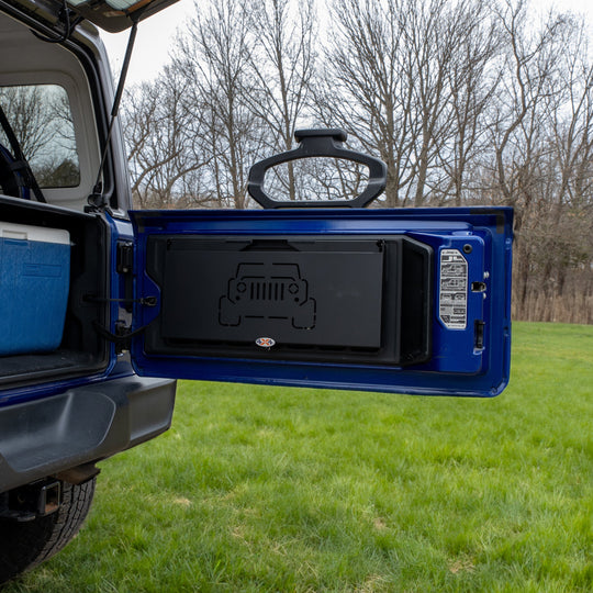 Tailgate table installed on Jeep shown folded up, highlighting space-saving design ideal for off-roading and camping.
