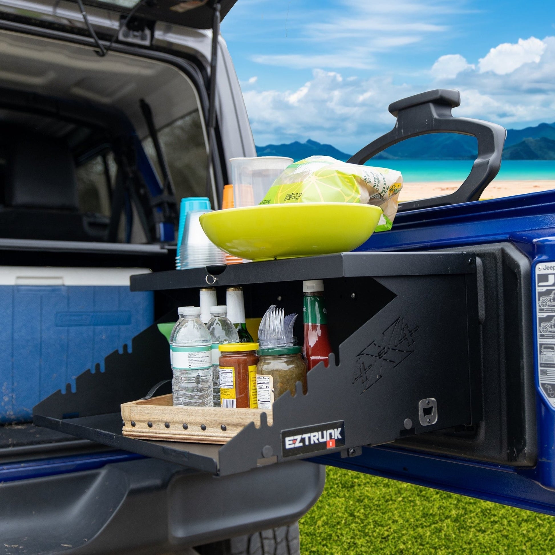 Extreme Folding Tailgate in blue Jeep holding condiments, utensils, food, and drinks for outdoor or tailgating use.