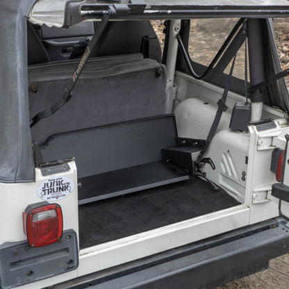 Black EZTrunk shown completely flat in cargo area of white Jeep TJ with trunk door open, highlighting low-profile fit.