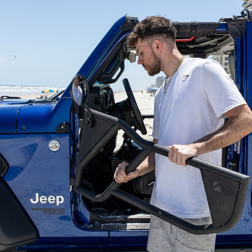 Man installing EZ4X4 Razor half-tube aluminum doors on blue Jeep, showcasing lightweight design and easy installation.