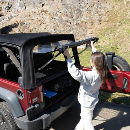 Woman setting up EZWindow in rear of red Jeep Wrangler, showing easy install and improved ventilation for off-road trips.