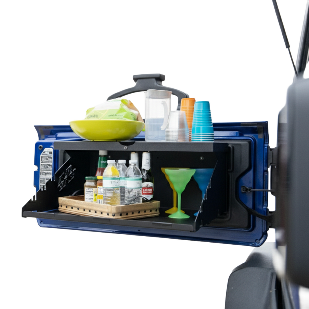 EZ4X4 Extreme Tailgate Table open on a blue Jeep, loaded with food, drinks, and cups on top and interior shelf.