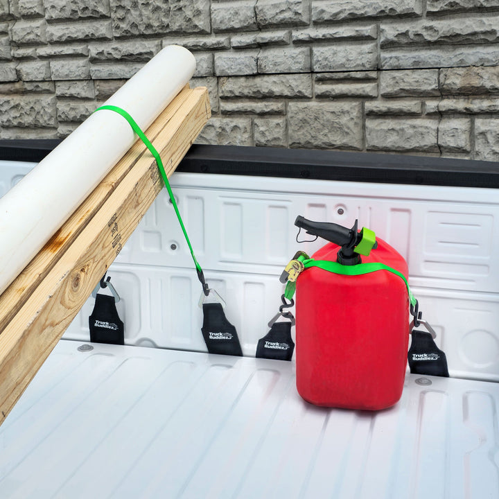 Two sets of Truck Buddiez straps securing red canister and lumber load for safe, stable truck bed cargo transport.