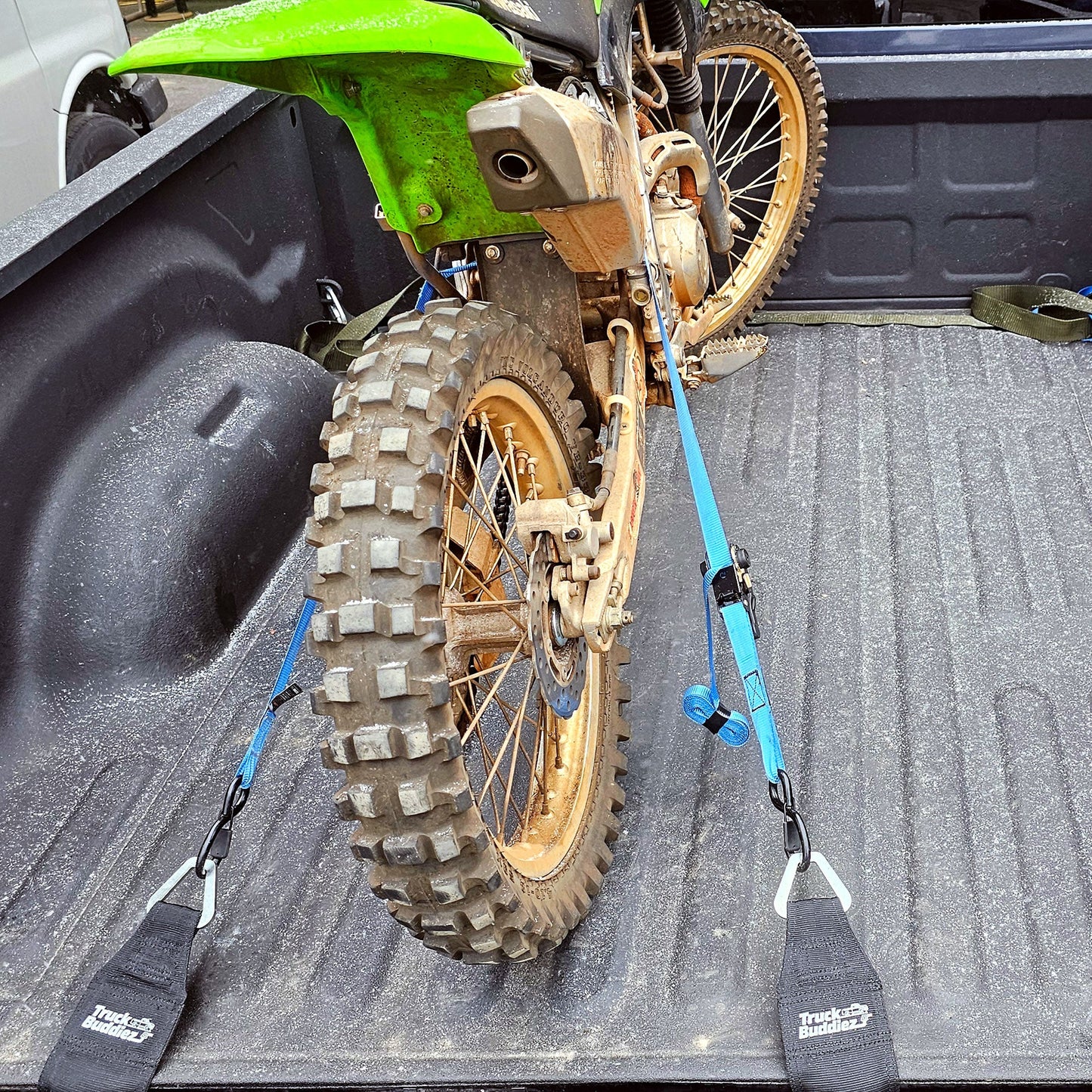 Dirt bike secured in truck bed with Truck Buddiez straps, showing adjustable, heavy-duty hold for off-road travel.